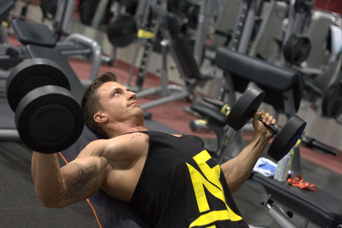 male fitness model doing the incline dumbbell press on an adjustable weight bench in a gym